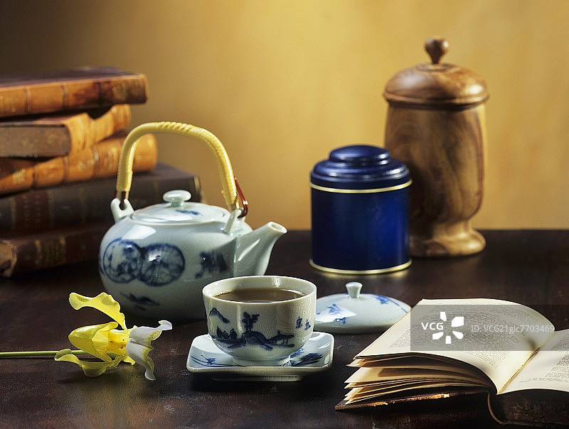 茶杯和壶中的绿茶，背景和前景中的书籍图片素材