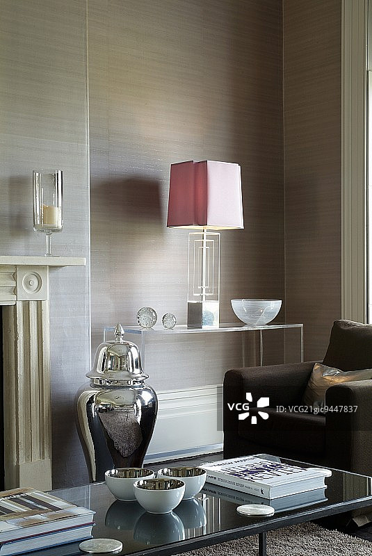 客厅角落的有机玻璃架子上的装饰艺术台灯前的棕色沙发图片素材