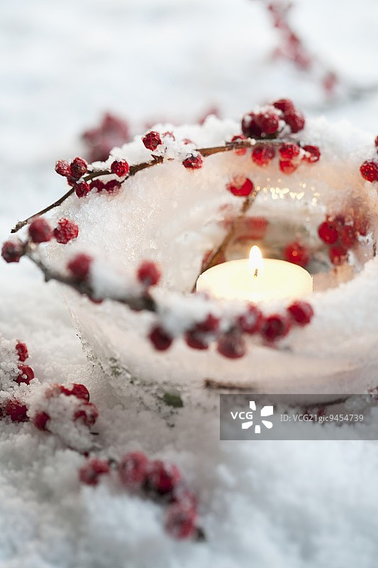 冰茶灯与冬莓和蜡烛在人造雪图片素材
