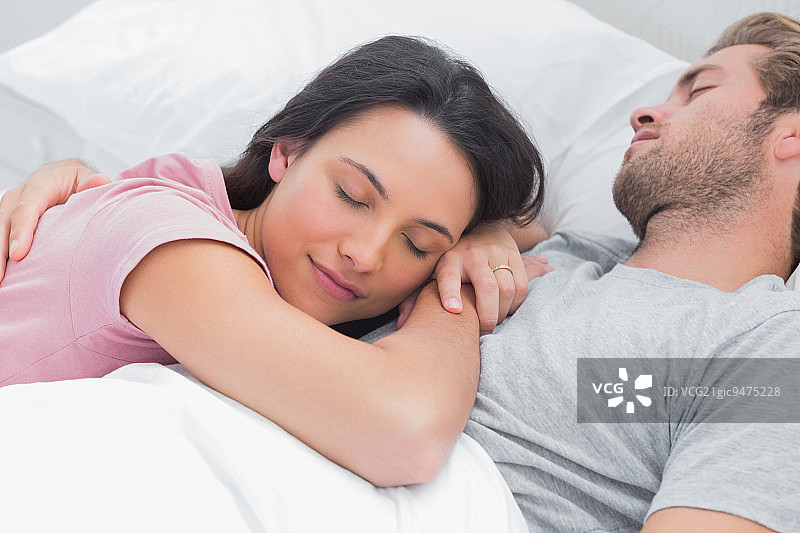 在床上，在丈夫的胸前平静地睡觉的女人图片素材