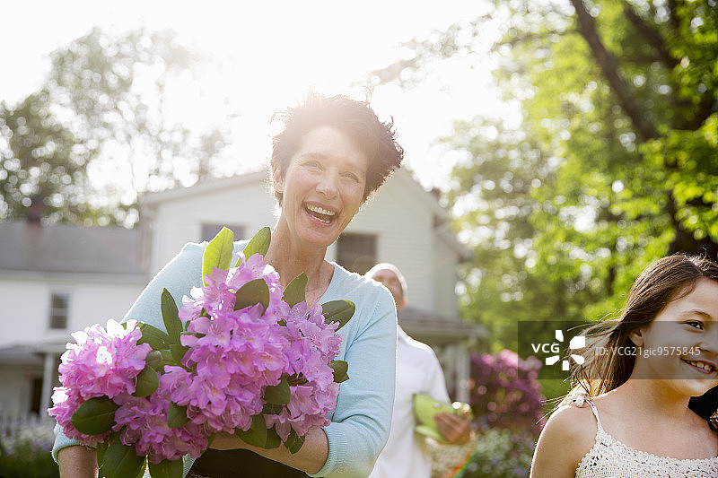 一个夏天在农场的家庭聚会。一位妇女捧着一大束杜鹃花，满面笑容。图片素材