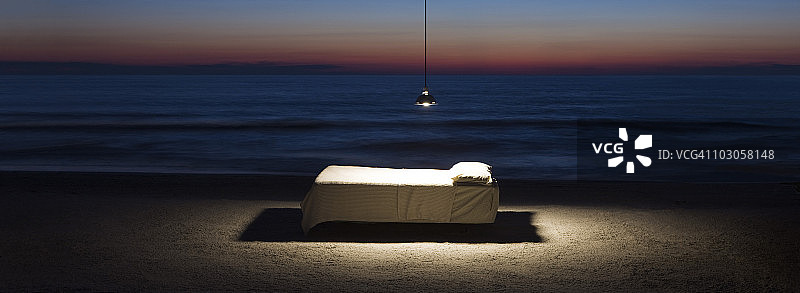 沙滩上的吊灯照亮的床图片素材