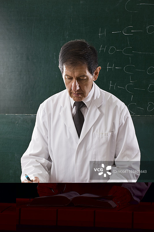 一位化学老师在教室里查阅教科书图片素材