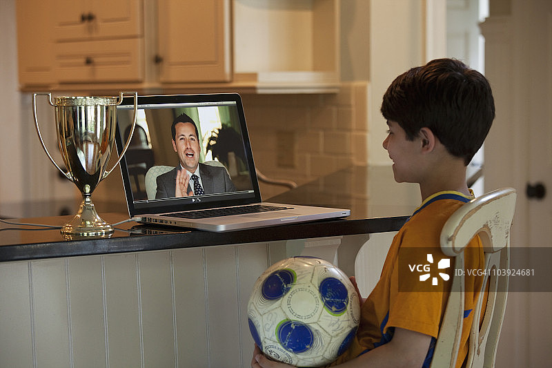 西班牙男孩用笔记本电脑看足球视频图片素材