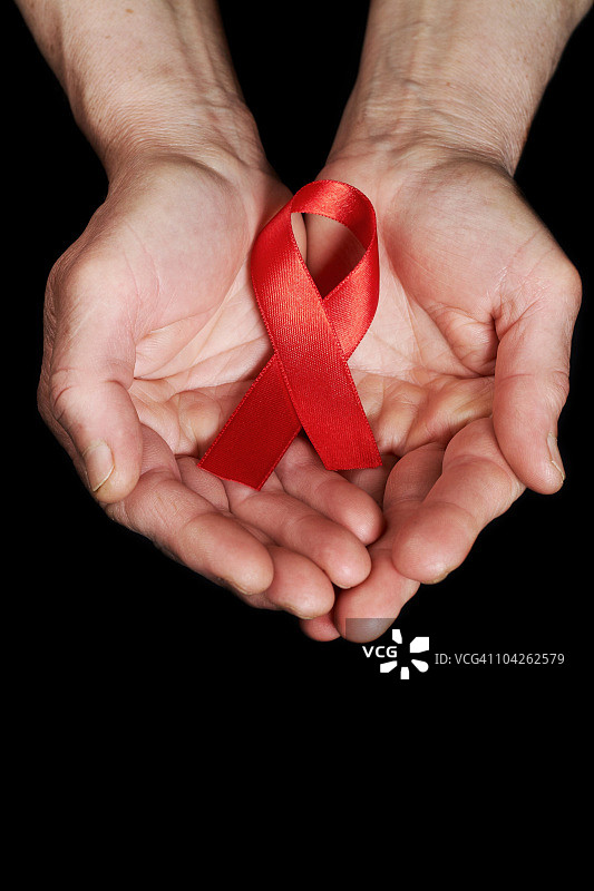 手握红色的艾滋病宣传丝带图片素材