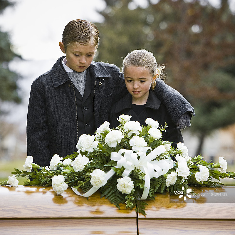 在墓地的葬礼上，哥哥搂着妹妹图片素材