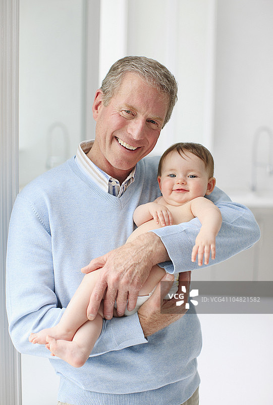 微笑的爷爷抱着婴儿图片素材