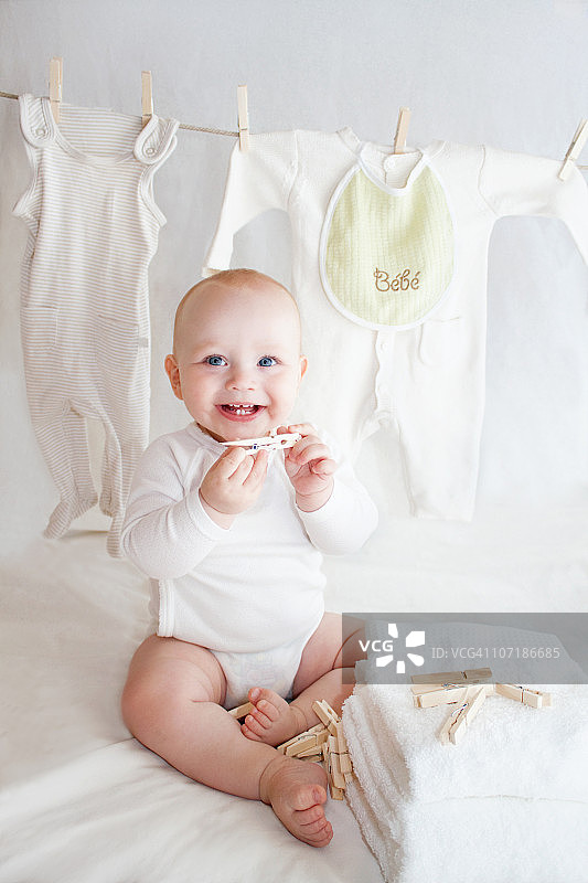 一个可爱的婴儿坐在晾衣绳旁图片素材