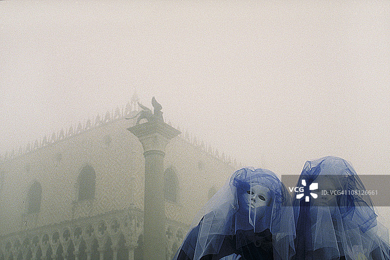 两个神秘的狂欢节面具，带着蓝色的面纱在迷雾中的威尼斯图片素材