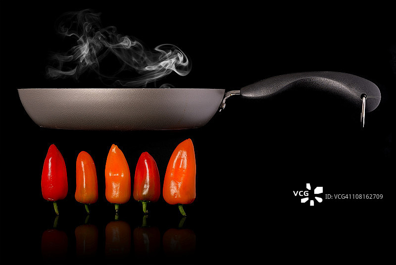 在黑底辣椒上煎锅烹饪图片素材