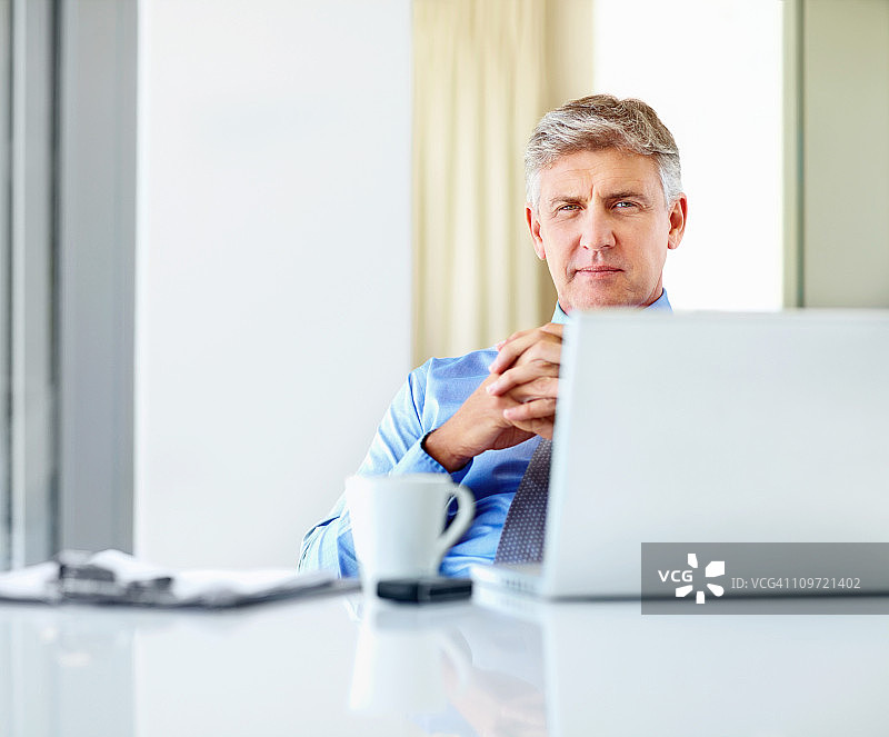 一个成熟的商人坐在电脑前工作图片素材