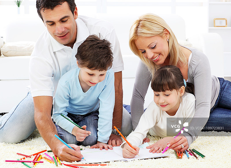 幸福的家庭。家长带着孩子用彩色铅笔画画。图片素材