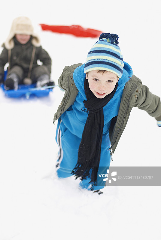 男孩用雪橇拉着他的朋友图片素材