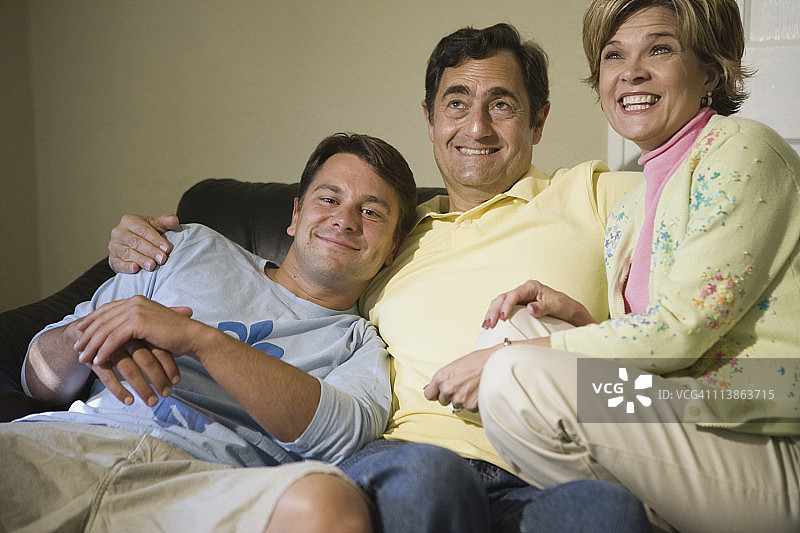 一家人坐在沙发上，面带微笑图片素材
