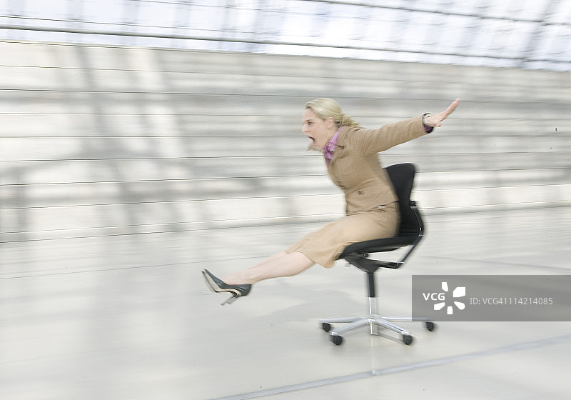 女人滑着办公椅图片素材