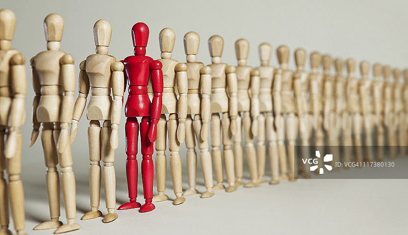 红色的人体模型站在一长排木制的人体模型中图片素材