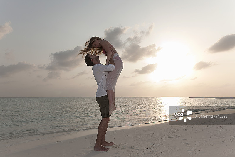 日落时分，一对情侣在海滩上玩耍图片素材