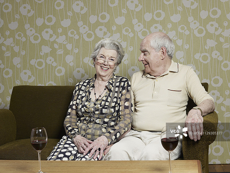 老夫妇在沙发上休息，桌上放着两杯葡萄酒图片素材
