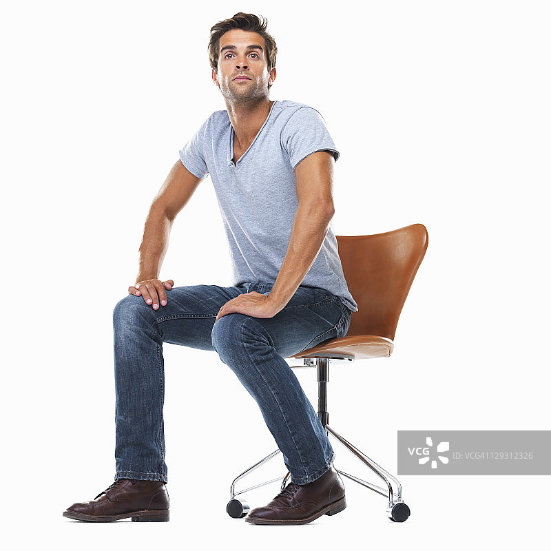 一名年轻人坐在椅子上，双手放在膝盖上图片素材