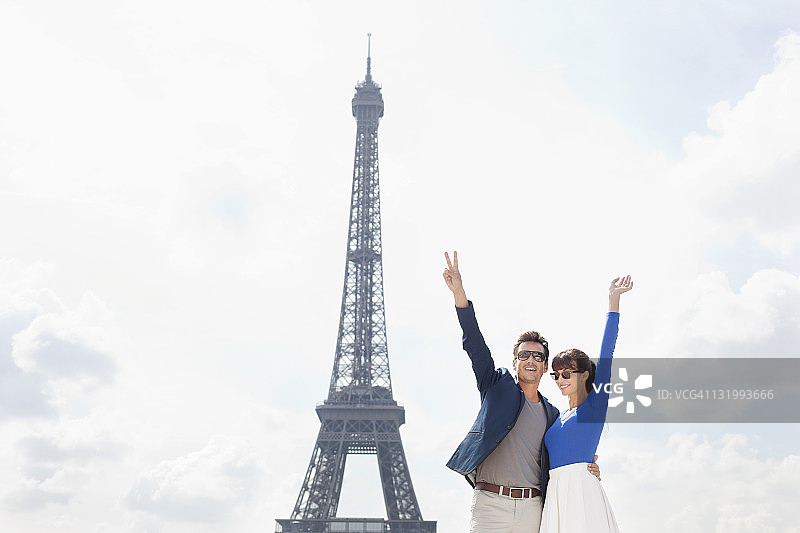 一对夫妇挥舞着双手，背景是埃菲尔铁塔，法国巴黎图片素材