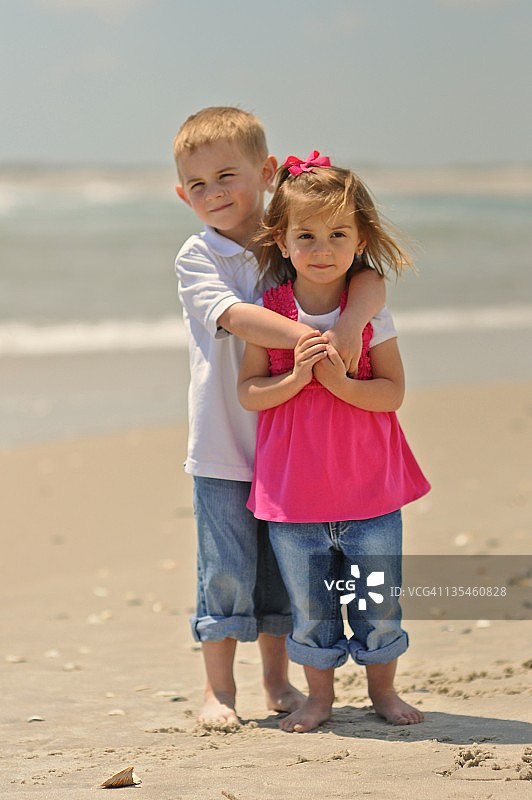 小男孩和小女孩站在海滩上图片素材