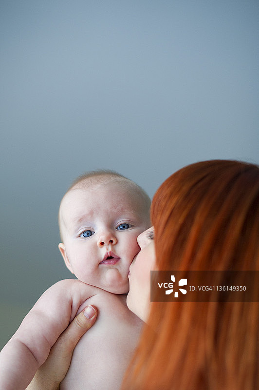 母亲亲吻女婴(4-6个月)。图片素材