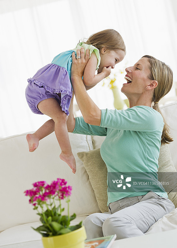 母亲和女儿(2-3)在沙发上玩耍图片素材