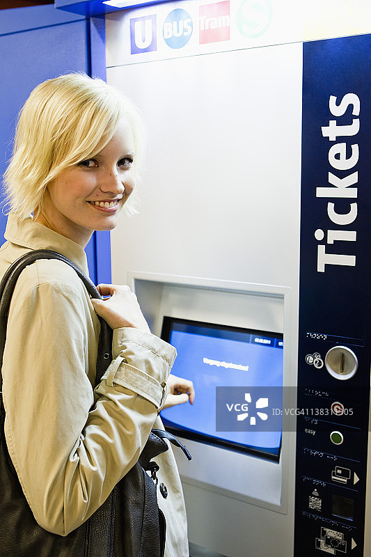 德国，巴伐利亚，慕尼黑，一名年轻女子站在地铁站售票机前图片素材