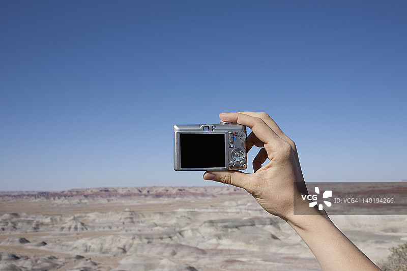 美国，亚利桑那州，温斯洛，女人的手举着相机，对着蓝天图片素材