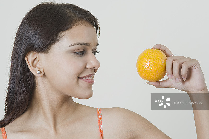 女人拿着橘子微笑着图片素材