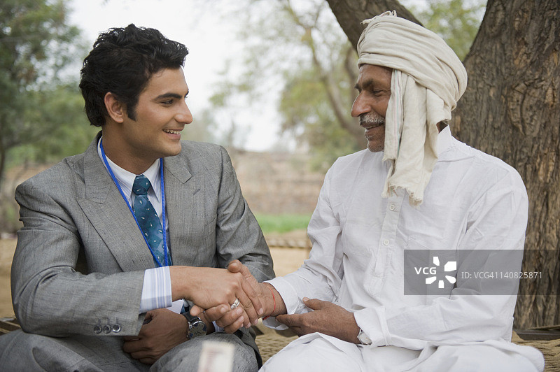 印度哈里亚纳邦哈森普尔，金融顾问与一位农民握手图片素材