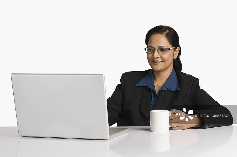 女商人一边用笔记本电脑工作一边喝咖啡图片素材