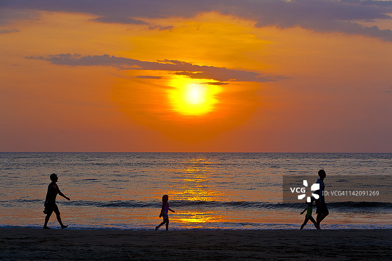 马来西亚沙巴州，日落时分，一家人在海滩上散步图片素材