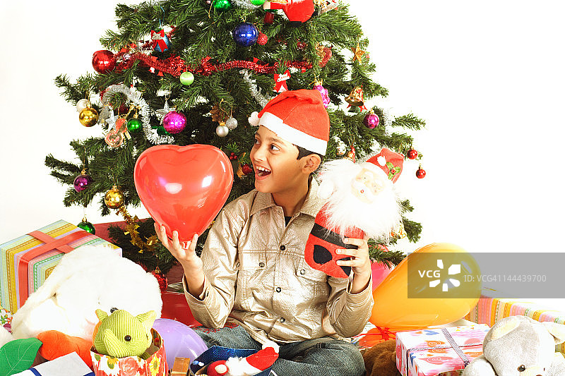 一个小男孩兴奋地坐在圣诞树下图片素材