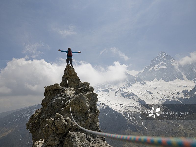 攀登者站在一望无际的峰顶，双臂伸开图片素材