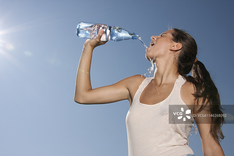 年轻女子在户外喝瓶子里的水图片素材