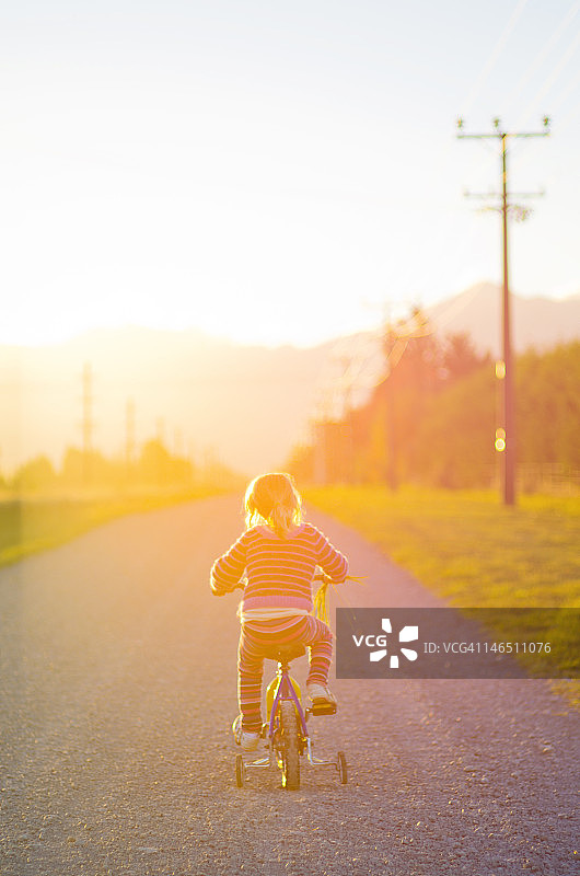 女孩骑着自行车在土路上图片素材