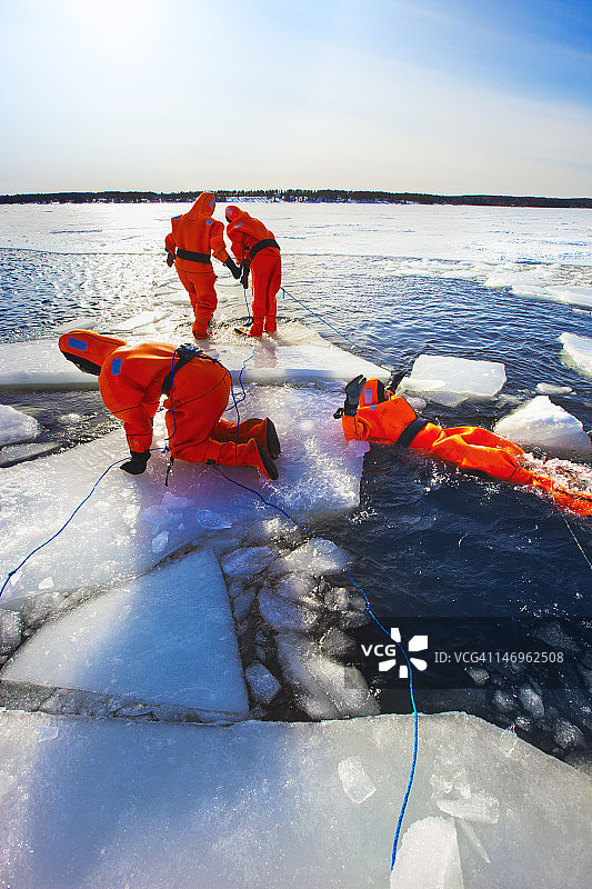 穿着氯丁橡胶衣服在冰冻的海里游泳。图片素材