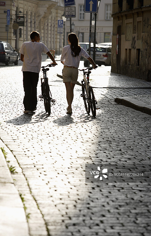 一对年轻夫妇在鹅卵石街道上骑自行车图片素材