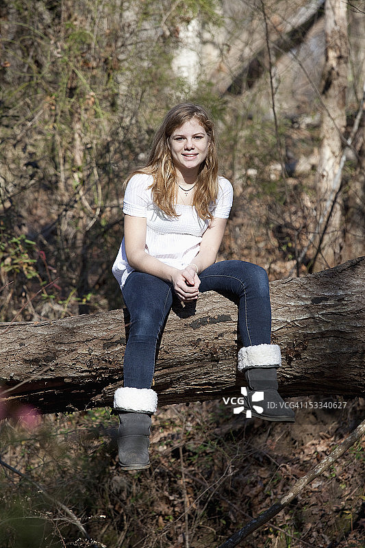 美国北卡罗来纳州穆尔斯维尔，一名女孩坐在树干上图片素材