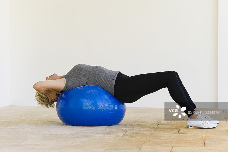 女人躺在健身球上图片素材