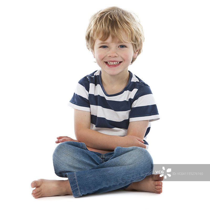 小男孩盘腿坐在白布上微笑图片素材