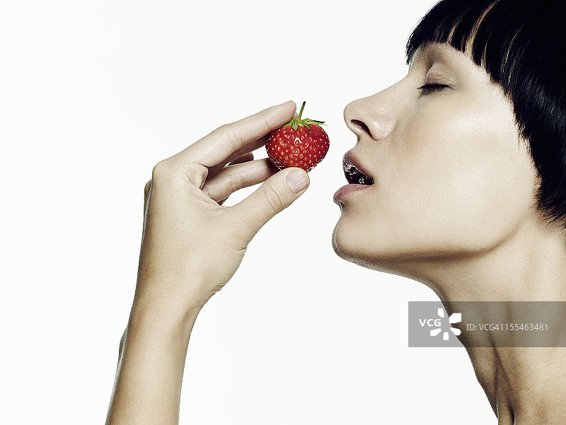 女人闻草莓的肖像图片素材