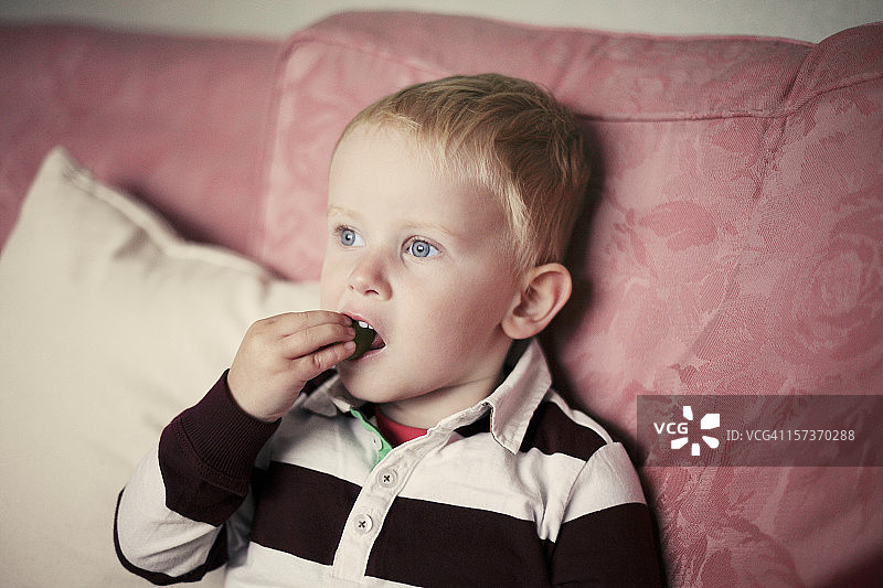 小男孩在沙发上吃东西图片素材