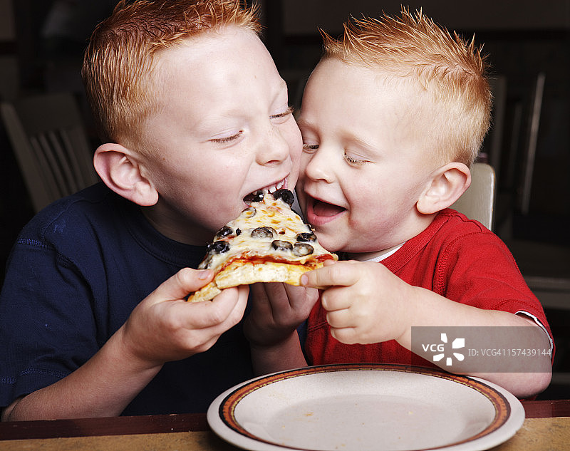 两个红发小兄弟为了一块披萨而打架图片素材