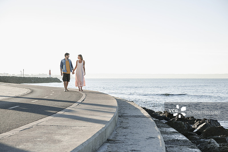 西班牙，一对中年夫妇沿着海岸散步图片素材