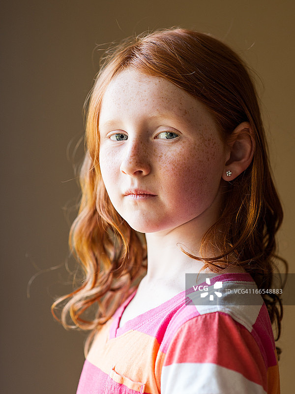 年轻的红头发女孩，戴着新穿的耳洞图片素材