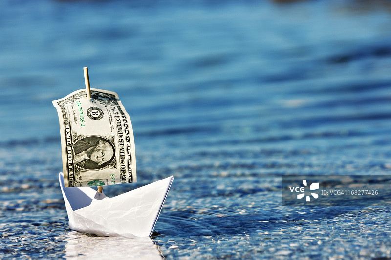 漂浮在一个公司吗?纸船与美元钞票航行图片素材
