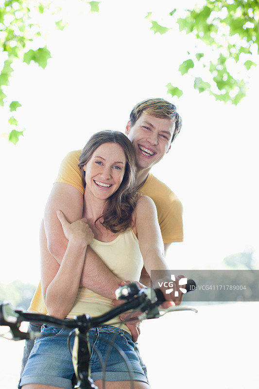 微笑的女人骑着自行车的男朋友图片素材