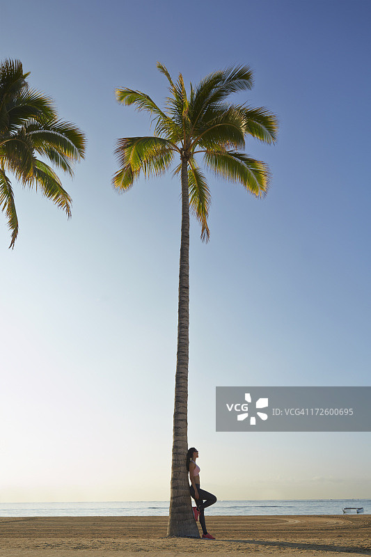 一位太平洋岛民倚靠在棕榈树上图片素材
